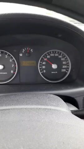 The video shows a close-up view of a car's dashboard while the vehicle is in motion. The speedometer needle hovers around 60 km/h. The odometer displays a reading of 159028. The fuel gauge is slightly above empty. The steering wheel and wiper controls are visible in the foreground, slightly obscuring the full view of the dashboard. The environment is suggested to be outdoors and the view is from inside the car facing towards the dash, focusing on the speedometer.