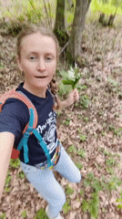 Woman gathers lily-of-the-valley flowers in Ukrainian forest setting