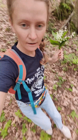 Woman gathers lily-of-the-valley flowers in Ukrainian forest setting