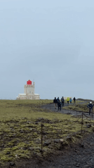 Tourists visit Iceland's Reynisfjara black sand beach under foggy skies