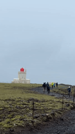 Tourists visit Iceland's Reynisfjara black sand beach under foggy skies