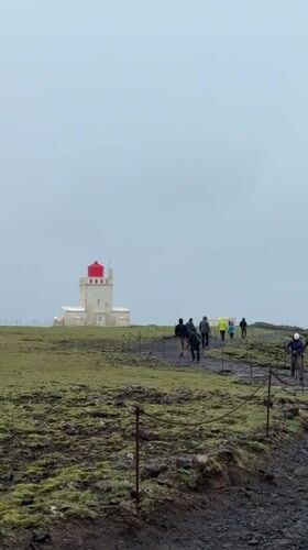 Tourists visit Iceland's Reynisfjara black sand beach under foggy skies