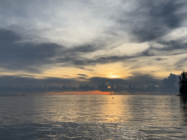 Golden sunset captured through clouds at Thai coastal village