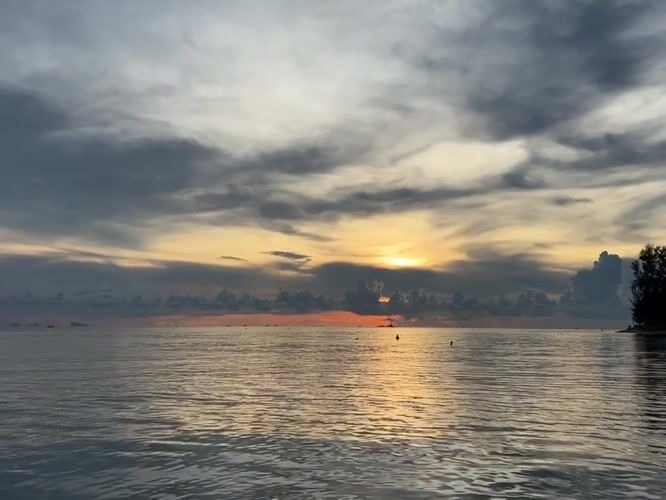 Golden sunset captured through clouds at Thai coastal village