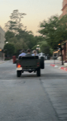Green Jeep with children drives down brick street