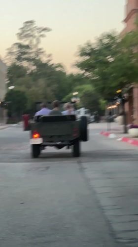 Green Jeep with children drives down brick street