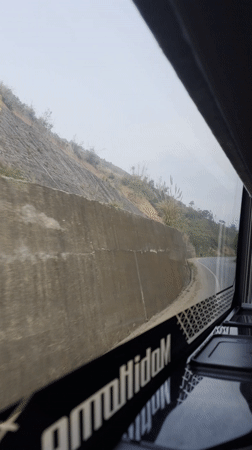 Vehicle travels winding hillside road in foggy Vietnam evening