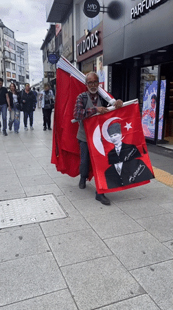 Man carries Turkish flags on busy Kadıköy street