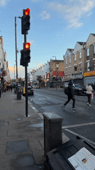 Evening street scene captured in London with pedestrians, red lights