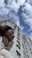 Woman gazes up at white apartment building in Russia