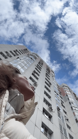 Woman gazes up at white apartment building in Russia