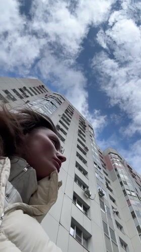 Woman gazes up at white apartment building in Russia