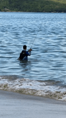 Man fishing in shallow ocean waters at Kuta beach