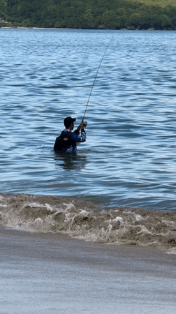 Man fishing in shallow ocean waters at Kuta beach