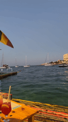 Dusk settles over a Maltese waterfront with sailboats and Gothic spires