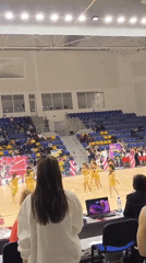 Dance troupe performs synchronized routine in gold outfits on basketball court