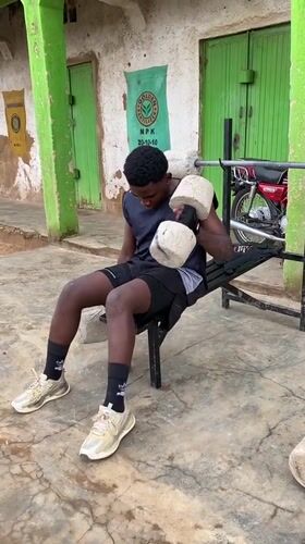 Young man exercises with makeshift concrete weights in Nigeria