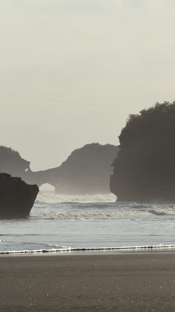 Beach visitors enjoy morning at Bali's dark sand shores