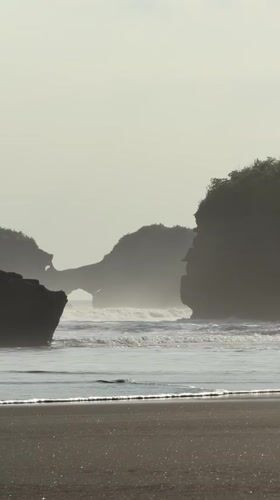 Beach visitors enjoy morning at Bali's dark sand shores