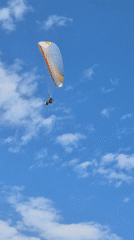 Paragliding session with colorful wings against blue skies