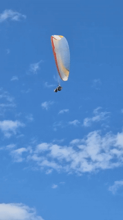 Paragliding session with colorful wings against blue skies