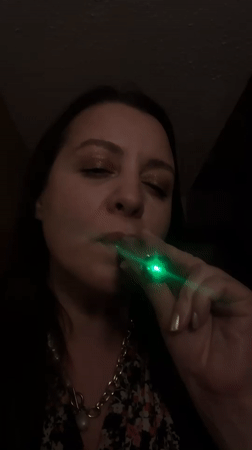 Woman vapes with glowing green e-cigarette in Riga interior