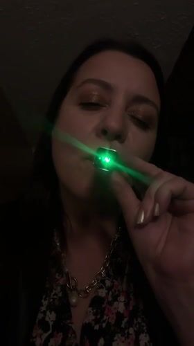 Woman vapes with glowing green e-cigarette in Riga interior