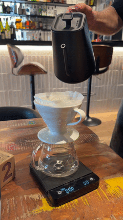 Man prepares pour-over coffee with precision equipment in Tarquinia