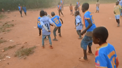 Children play soccer on dirt field in rural Congo