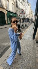 Woman in light blue spotted eating, walking in Paris