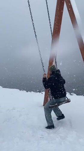 Man swings in heavy snowfall at Murmansk playground