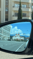 Car mirror reflects Russian street scene with domed building