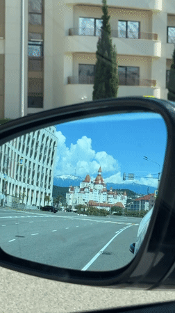 Car mirror reflects Russian street scene with domed building
