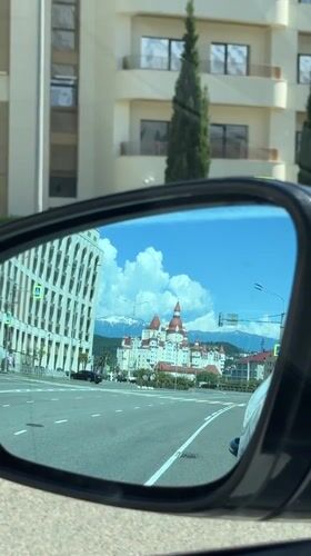 Car mirror reflects Russian street scene with domed building