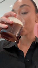 Woman drinks coffee, uses phone in Milan retail location