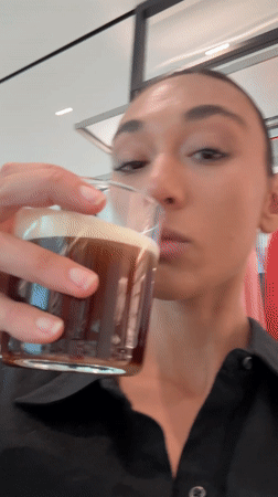 Woman drinks coffee, uses phone in Milan retail location
