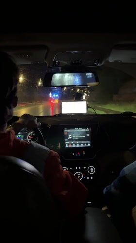 Nighttime drive on wet Batumi road with emergency lights ahead