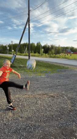 Child plays soccer in rural Russian village during afternoon