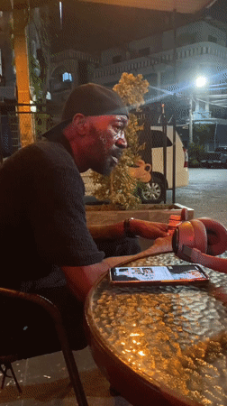 Man sits at outdoor table in Pattaya, appears singing