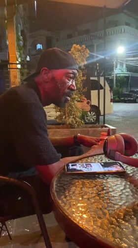Man sits at outdoor table in Pattaya, appears singing