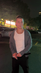 Young man walks, smokes on Tianhe District street at night