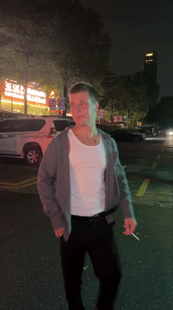 Young man walks, smokes on Tianhe District street at night