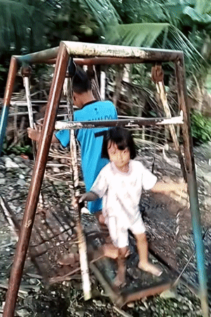Children play on swings in Indonesian backyard after midnight