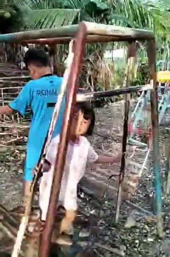 Children play on swings in Indonesian backyard after midnight
