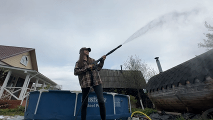 Woman operates pressure washer outdoors in Khokhryaki, Russia
