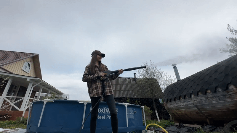 Woman operates pressure washer outdoors in Khokhryaki, Russia