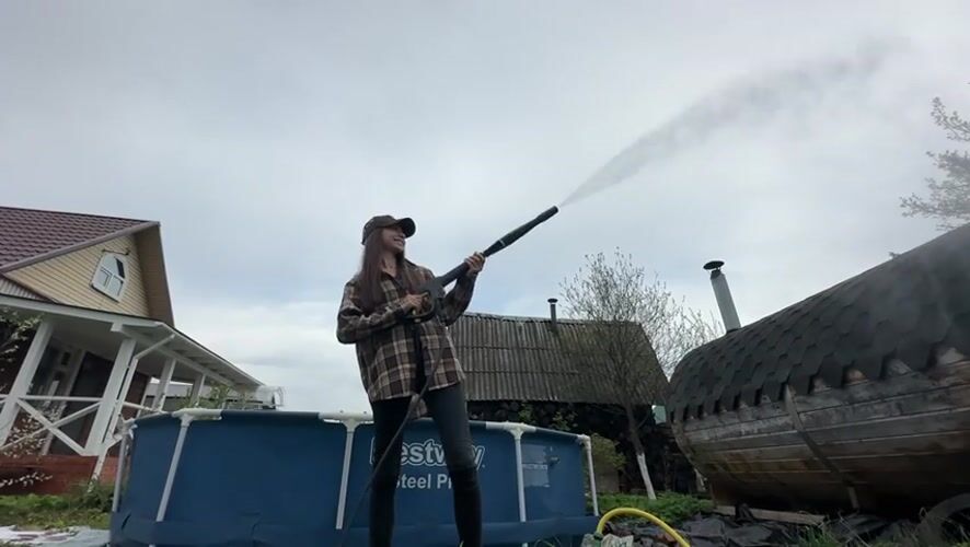 Woman operates pressure washer outdoors in Khokhryaki, Russia