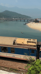 Vietnam Railways train travels riverside tracks in Huế