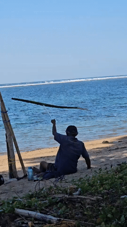 Quiet morning on Sanur Beach with boats, locals, and calm water