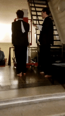 Two suited men stand barefoot, gesturing toward equipment in Saint Petersburg
